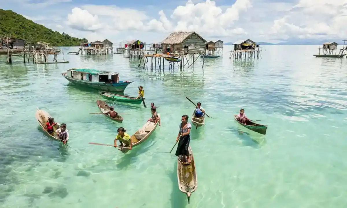 Local children skillfully paddling their small traditional boats in the waters of their sea village near Semporna.